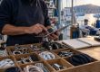 Commerçant tenant une tablette au comptoir d'une boutique d'accastillage près du port de Toulon, entouré de cordages et pièces nautiques.